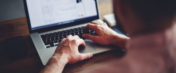 Cropped image of a young man working on his laptop in a coffee shop, rear view of business man hands busy using laptop at office desk, young male student texting on computer sitting at wooden table