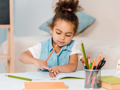 beautiful african american child studying and writing with pencil
